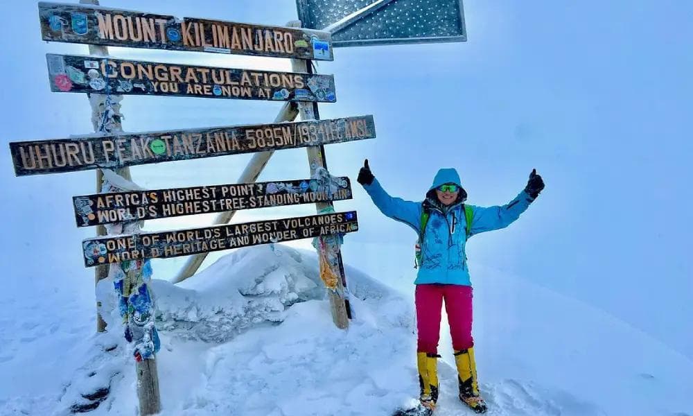Climber celebrating at the Uhuru Peak summit sign